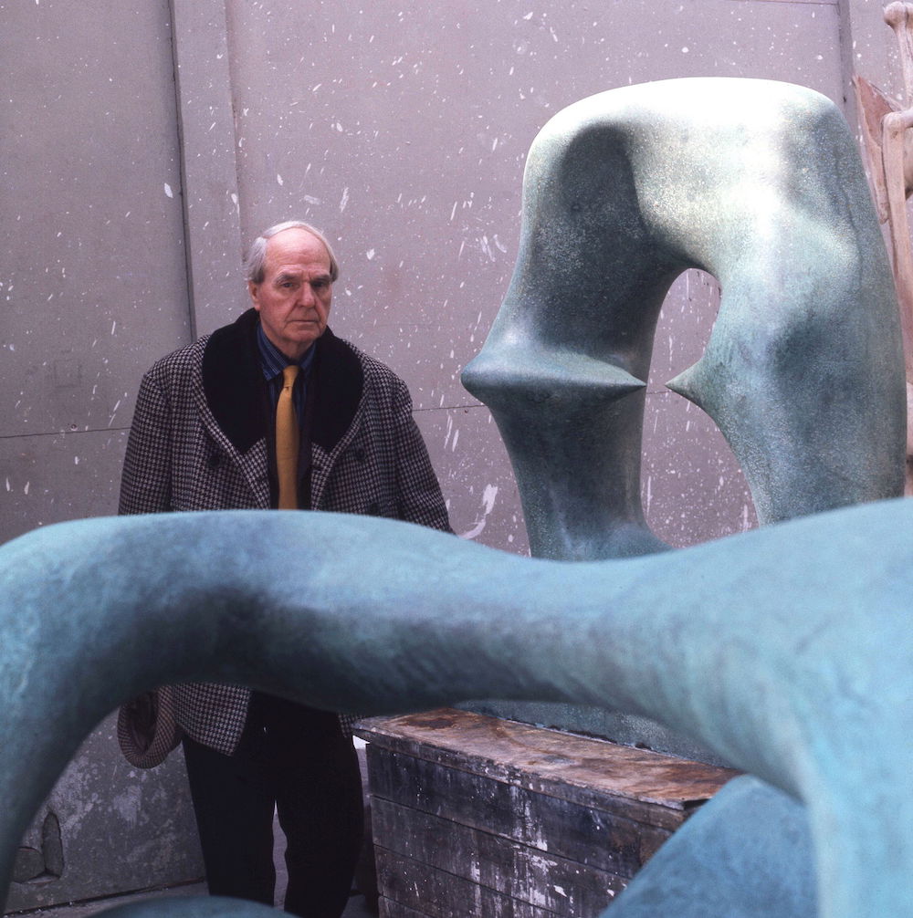 Henry Moore, posing beside his sculpture Working Model for Oval with Points