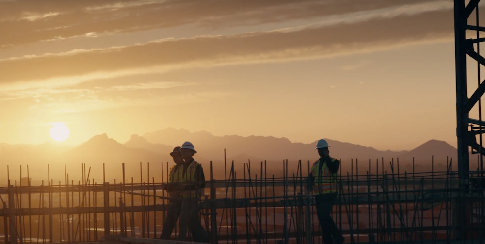 Construction workers on a site overlooking the mountains at sunrise