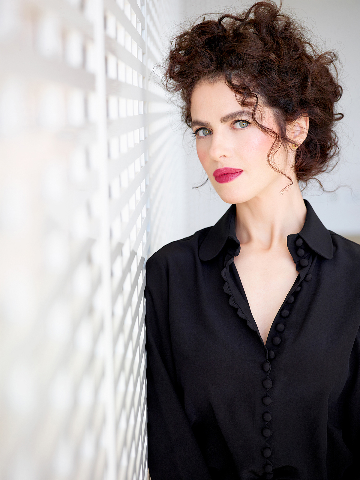 A profile of architect Neri Oxman leaning up against a white wall.